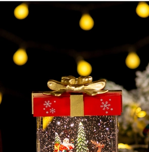 Macro view of Christmas snow globe featuring Santa Claus and reindeer inside a gift box