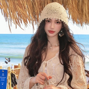 Dettaglio cappello da sole beige all'uncinetto stile boho con nappe di perle bianche
