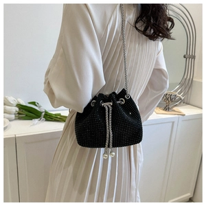 Detail of a black rhinestone bucket bag with silver chain strap and pearl drawstring