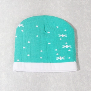 Detail of teal Christmas knit hat featuring white snowflakes and a cozy cuffed hem