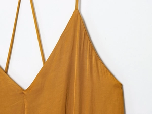 Detail of thin spaghetti straps and deep V-neckline on mustard satin midi dress