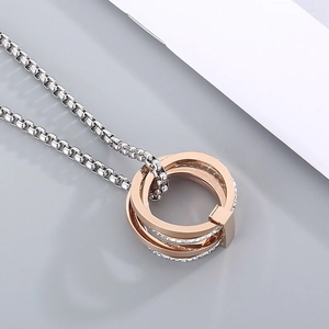 Macro shot of interlocking rose gold and diamond-set silver rings on a box chain