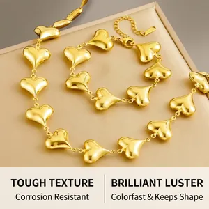 Polished gold stainless steel jewelry set with heart-shaped links on a display tray