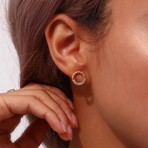 Macro close-up of gold-plated twisted hoop earrings with micro-pave crystals on model