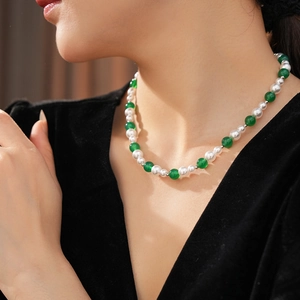 Dettaglio di elegante collana vintage con agata verde e perle bianche su una modella