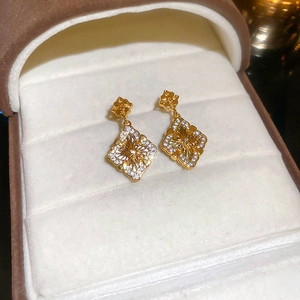 Détail de boucles d'oreilles fleurs dorées avec zircon dans un coffret cadeau