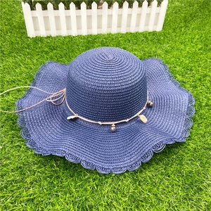 Détail du chapeau de soleil bleu avec bord ondulé et ornements de perles et coquillages