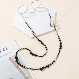 Detail of elegant eyewear chain with black stones, golden beads and striped accents