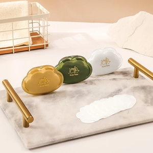 Cloud-shaped portable soap flake containers in yellow, green, and white on a marble tray