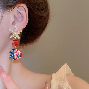 Detail of starfish and tropical fish earrings with red beads on a model for beach style