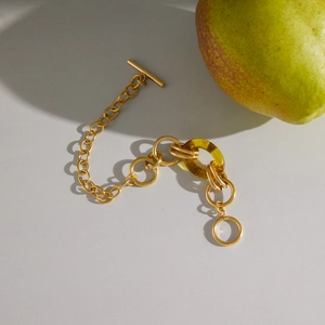 Minimalistisches Goldkettenarmband mit Knebelverschluss und bernsteinfarbenem Harzring