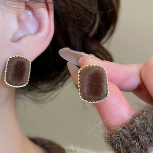 Close-up of square flocking stud earrings in deep brown with gold textured edges
