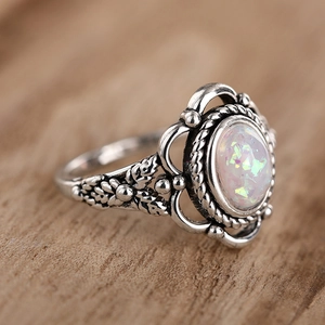 Macro shot of vintage silver ring featuring floral carvings and oval opal gemstone