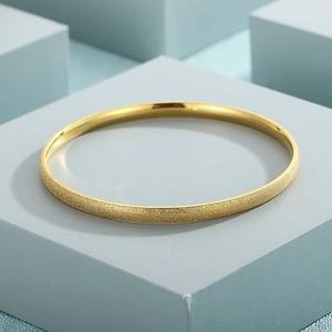 Close-up of golden titanium steel bangle showing contrast between matte and polished finishes