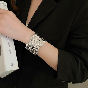 Detailed view of silver lava texture wide cuff bracelet on a model wearing a black suit