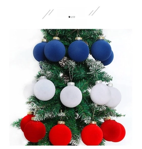 Detail of red, white, and blue flocked velvet Christmas balls hanging on a snowy tree branch