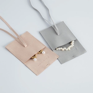 Detailed texture of microfibre jewelry pouches in dusty pink and grey with debossed logo