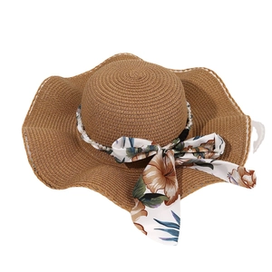Brown straw sun hat featuring elegant floral ribbon, pearl chain and wavy brim design