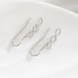 Macro shot of silver infinity twist earrings featuring a polished minimalist metal finish