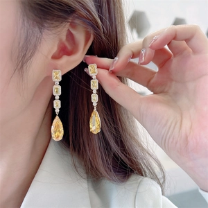 Macro shot of long champagne zircon teardrop earrings worn on ear for evening luxury style