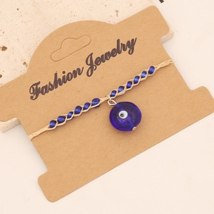 Bohemian woven seed bead bracelet featuring a blue evil eye charm on display card