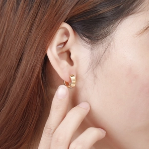 Close-up of a gold hoop earring set with zircon, showing model's ear for size and fit