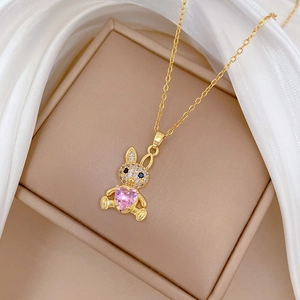 Detail of gold rabbit necklace with pink heart stone and white zircons on silk