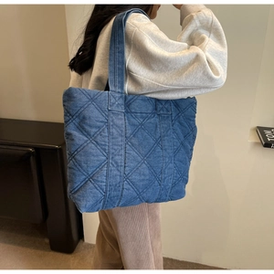 Détail d'un sac cabas en denim bleu avec un motif de surpiqûres en losange classique