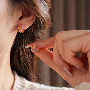 Close-up of a colorful flower stud earring with faceted crystal gems on a model's ear