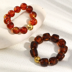Retro acrylic beaded bracelet with golden beads and amber square stones in natural sunlight