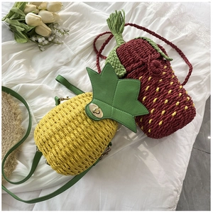 Detail of hand-woven pineapple and strawberry crossbody bags with metal turn locks
