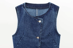 Dettaglio del top in denim blu scuro senza maniche con bottoni in metallo e girocollo