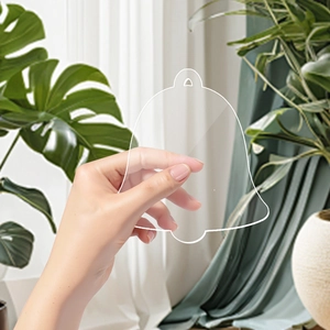Bell-shaped clear acrylic Christmas ornament held by hand for festive DIY decorations