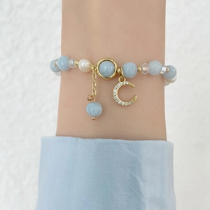Close-up of ocean blue beaded bracelet with white pearls and gold moon pendant