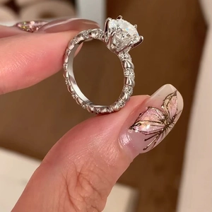 Classic silver ring with round center stone and pave diamonds held by elegant hands