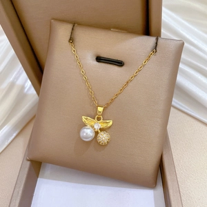 Detailed close-up of a gold cherry pendant necklace with inlaid pearls and sparkling zircons