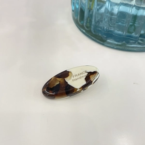 Detail of a handmade acetate hair clip with amber tortoise and cream contrast design