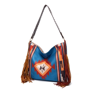 Detail of bohemian woven shoulder bag with orange tribal pattern and long brown tassels