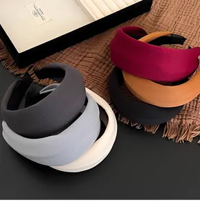 Stack of thick sponge headbands in various colors on a textured brown fabric background