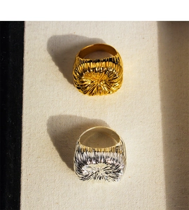 Macro view of gold and silver rings with unique radial pleated texture and metallic finish