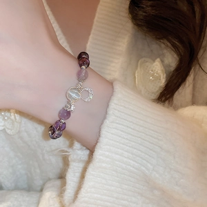 Detail of beaded bracelet with purple stones and moon charm on a model's wrist