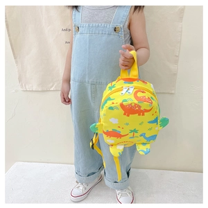 Detail of yellow canvas kids backpack featuring colorful dinosaur prints and side wings
