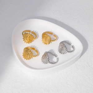 Close-up of adjustable gold and silver letter rings on a white ceramic tray