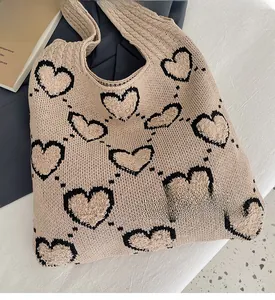 Détail macro du sac fourre-tout en maille beige avec motifs de cœurs noirs en peluche 3D