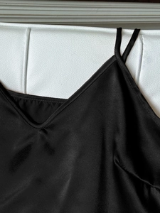 Detaillierte Makroansicht des schwarzen Satin-Unterhemds mit V-Ausschnitt und Trägern
