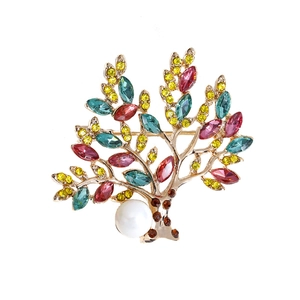Elegant gold tree brooch with colorful crystals and a white pearl on a white background