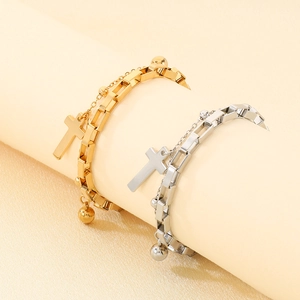 Detail of double-layered cross bracelet in gold and silver hanging on cylindrical props