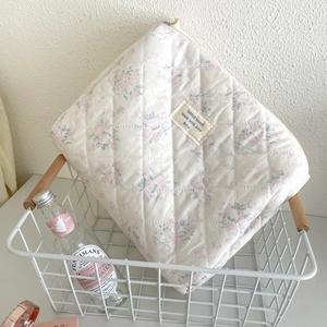 Detail of quilted cotton floral makeup bag with a vintage label in a decorative basket