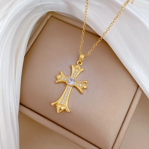 Luxurious gold titanium cross necklace with sparkling crystals on elegant silk background