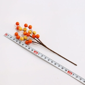 Artificial red and yellow holly berry branches shown with ruler measuring 20cm length